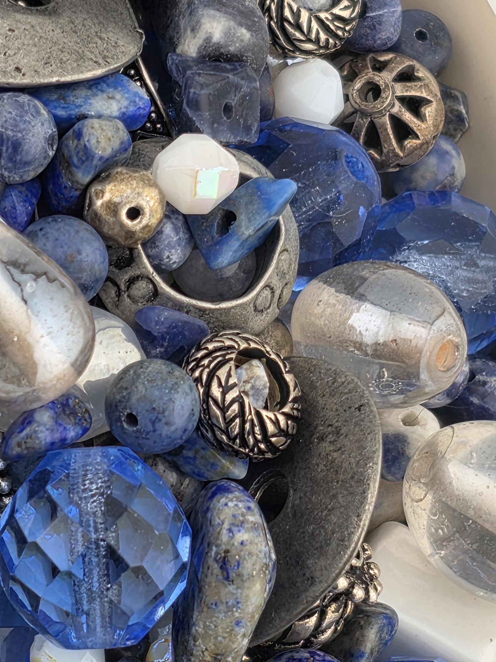 a variety of colorful beads and metal objects, including blue, silver, and white beads, as well as metal pieces with intricate designs.