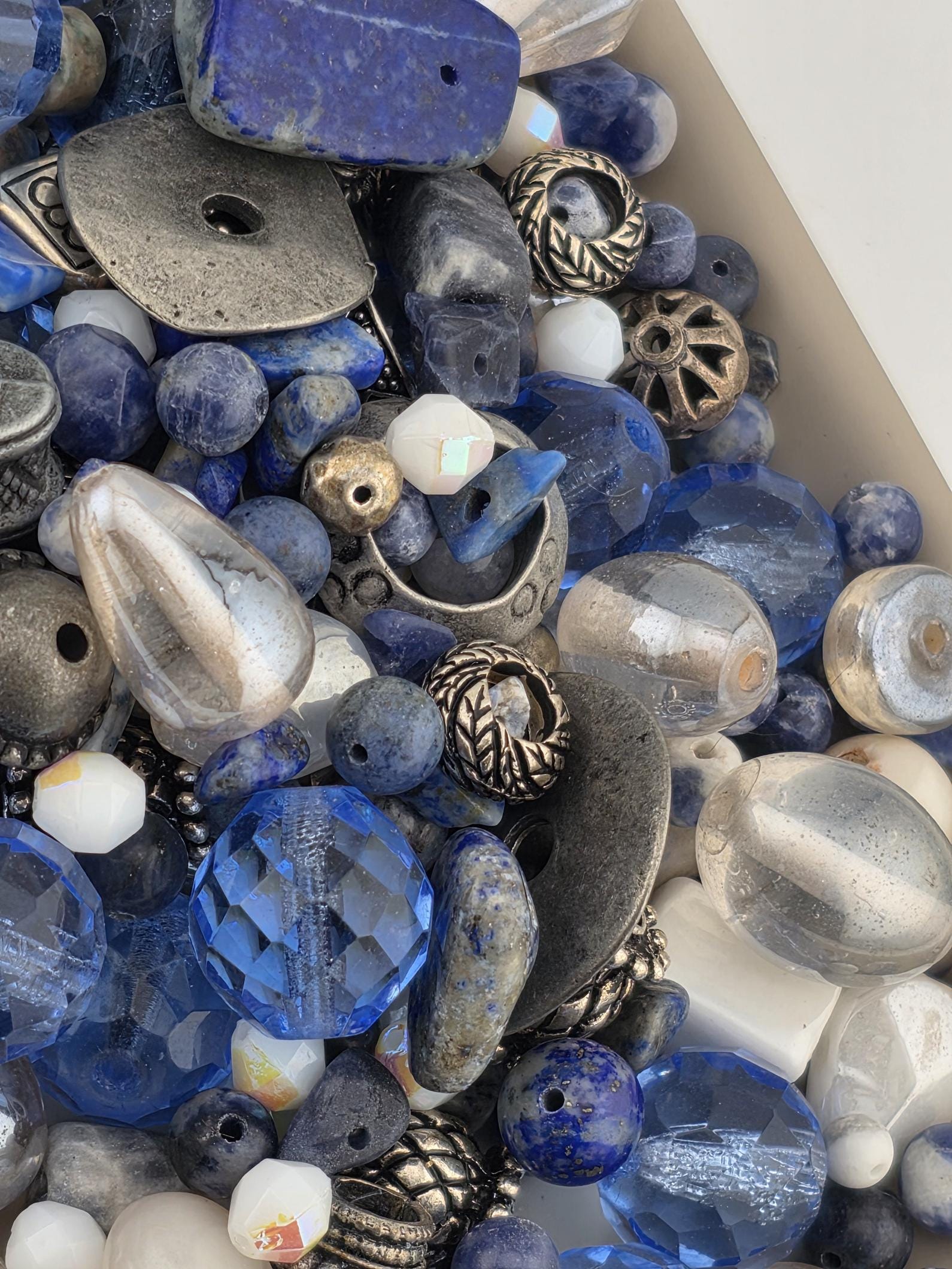 a variety of colorful beads and jewelry pieces, including clear and blue beads, silver and black beads, and other decorative elements.