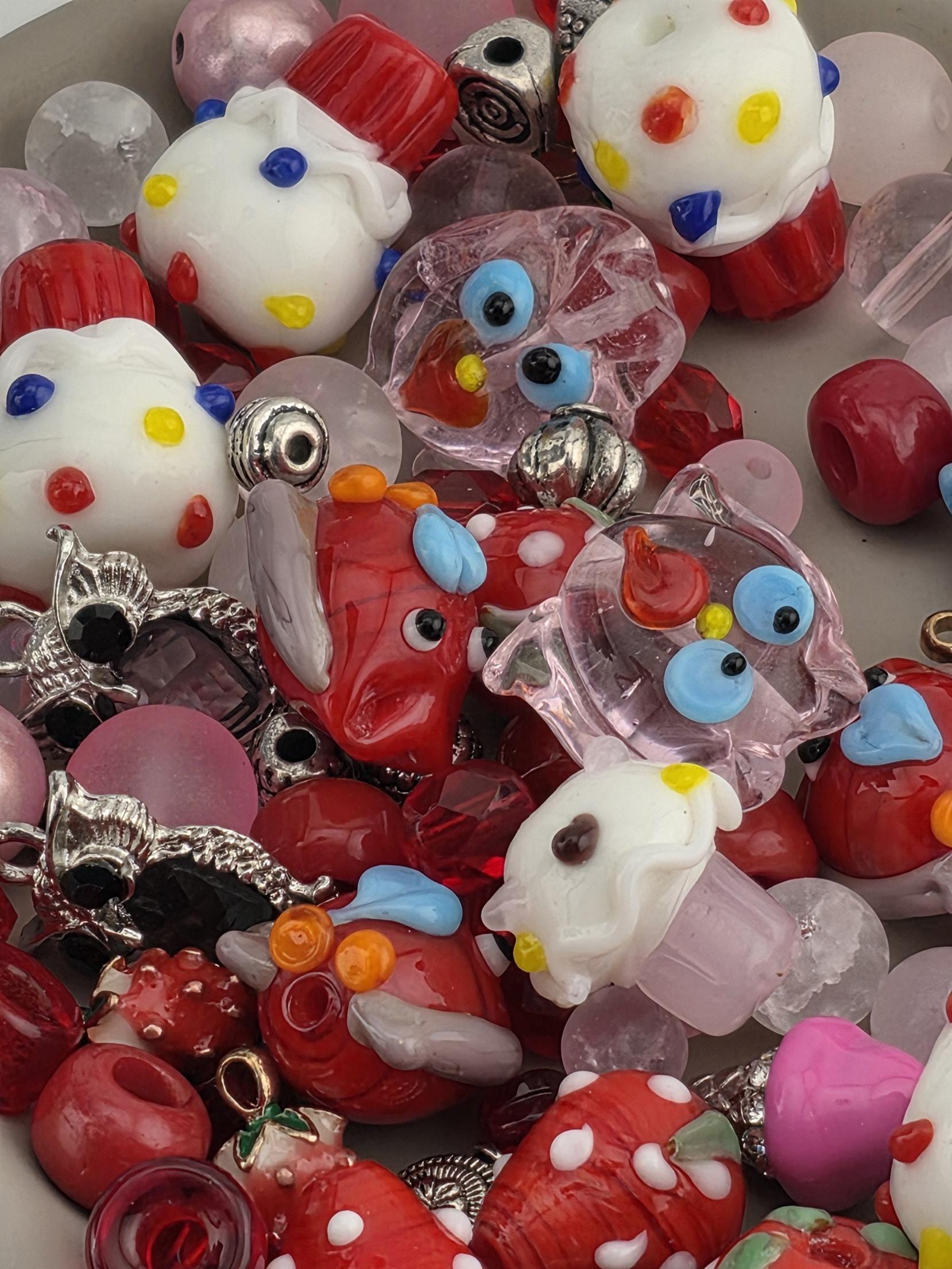 A colorful assortment of beads, charms, and other decorative items, including a variety of shapes and colors such as red, white, blue, and yellow.