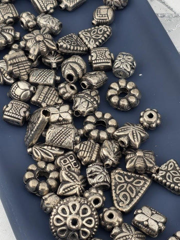 a collection of various metal beads and charms scattered on a blue surface.