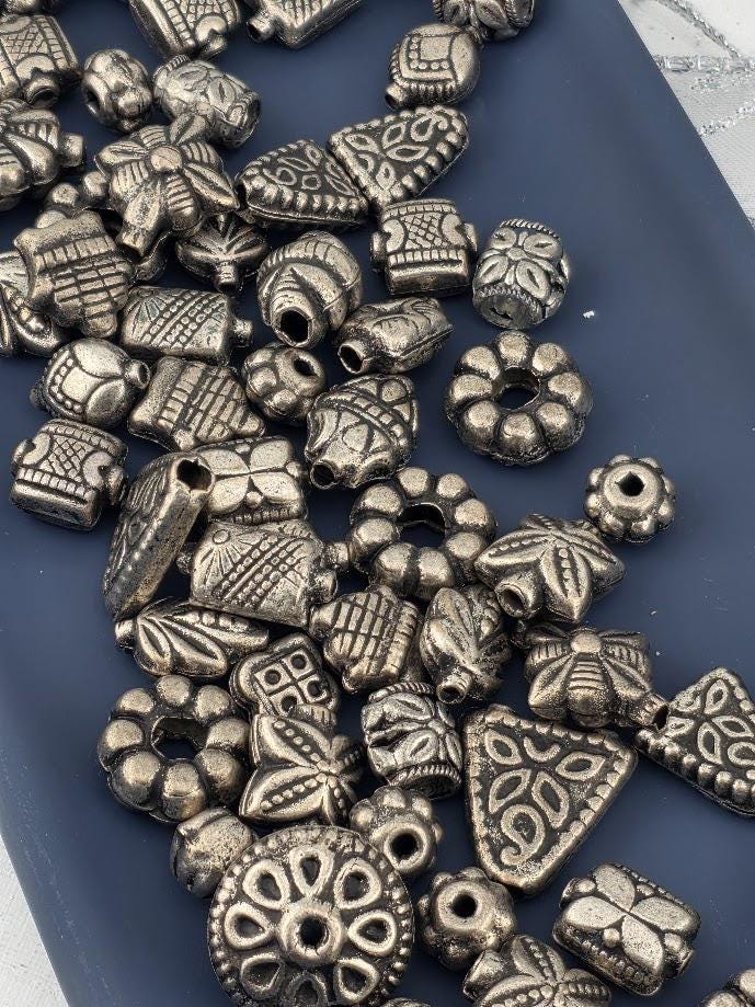 a collection of various metal beads and charms scattered on a blue surface.