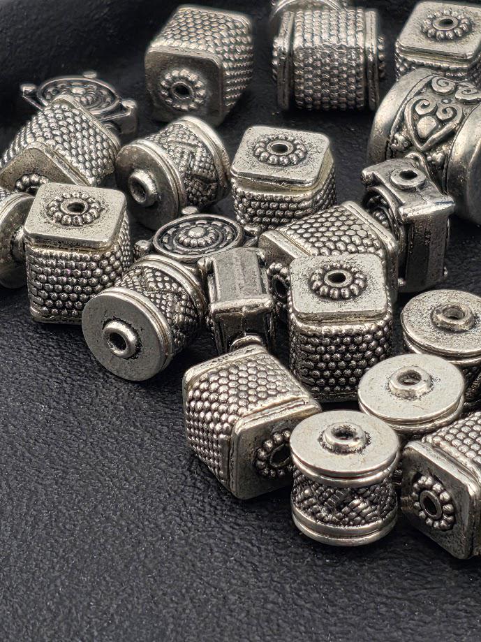 a collection of various metal beads and beads in different shapes and sizes, arranged on a dark surface.