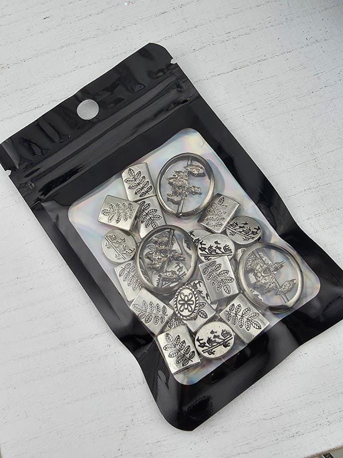 A black and clear plastic bag containing various metal charms or pendants with intricate designs.
