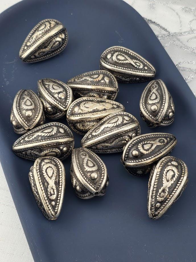 a collection of ornate metal beads arranged on a blue surface.