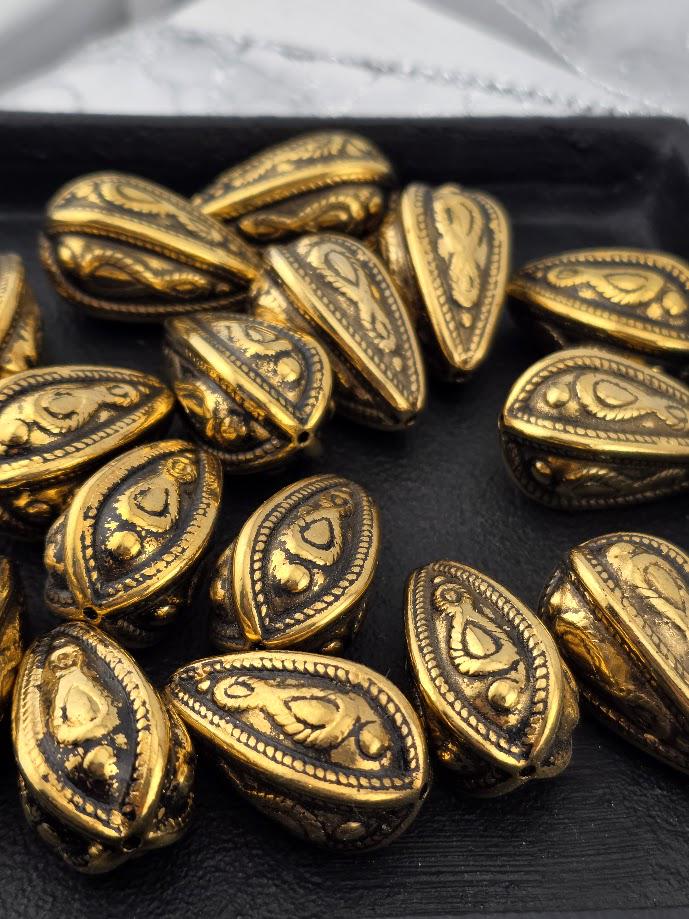 a collection of ornate, golden-colored metal beads arranged on a black surface.