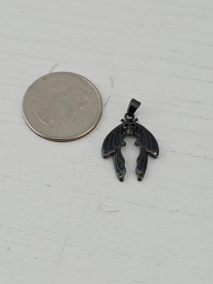 A silver coin next to a small metal pendant in the shape of a butterfly.