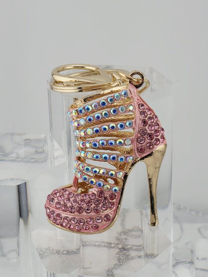 A keychain in the shape of a high-heeled shoe, adorned with rhinestones and gold accents.
