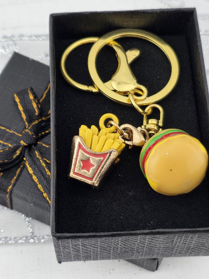 A keychain with a gold-colored metal ring and a small toy hamburger, along with a small red and gold french fry container.