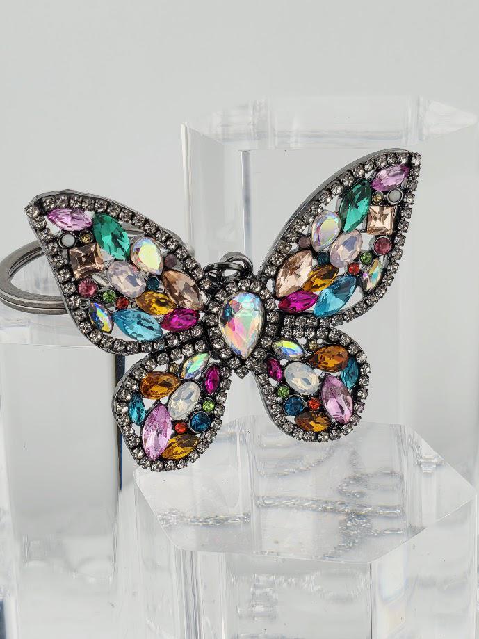 A colorful butterfly-shaped pendant made of various gemstones and jewels, including diamonds and gemstones in different colors and shapes.
