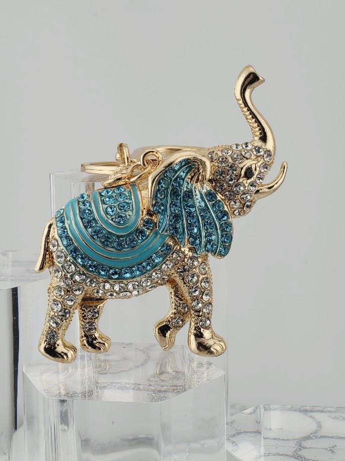 A decorative elephant brooch with a gold and blue color scheme, adorned with sparkling rhinestones.