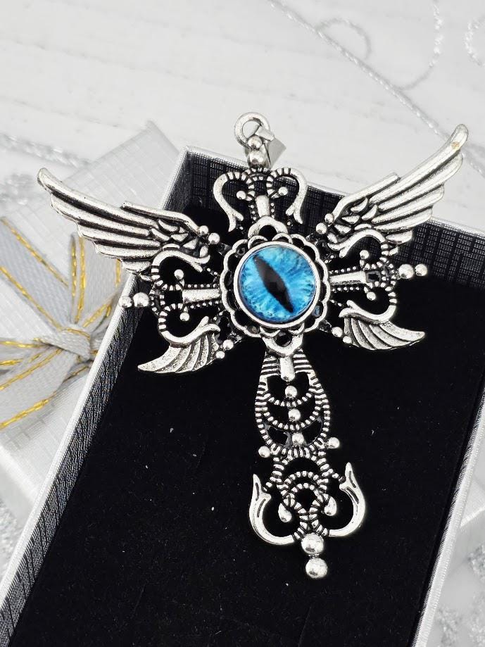 A silver-toned pendant with a blue eye design, featuring intricate wing-like patterns and a central eye-shaped element.