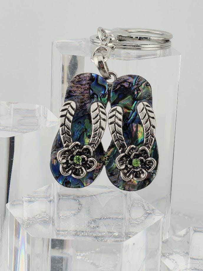 A pair of colorful, flower-shaped earrings with a silver metal frame, displayed on a clear glass stand.