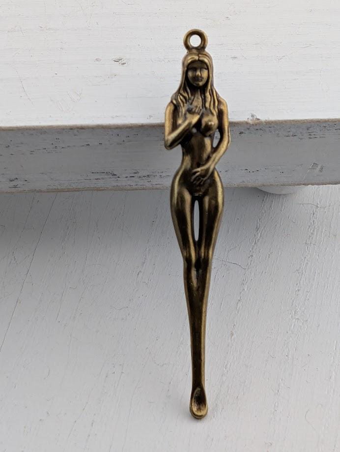 A bronze sculpture of a naked female figure is displayed on a white surface.