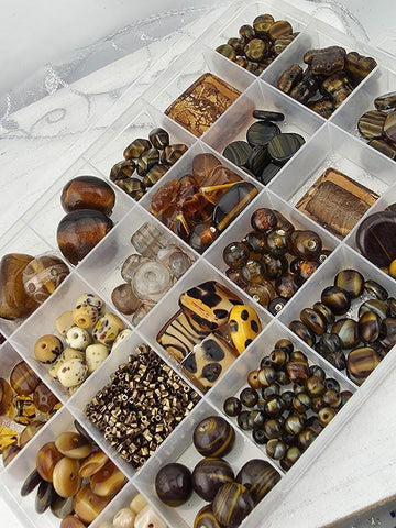 A clear plastic container filled with various beads and beads in different shapes and sizes, organized into multiple compartments.