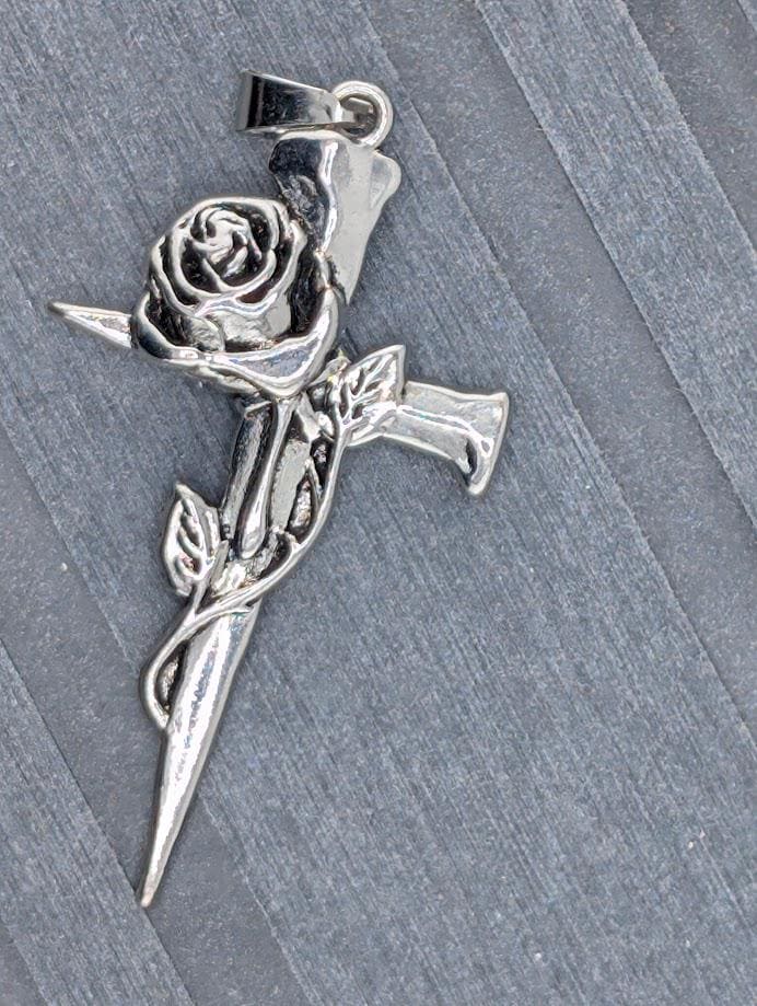 A silver-colored pendant in the shape of a rose is displayed in a black box with a white ribbon.