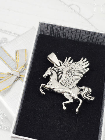 A silver pendant in the shape of a winged horse or mythical creature is displayed in a black box with a gold ribbon.