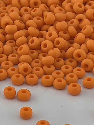 a large pile of orange beads or beads, with some scattered on a white surface.