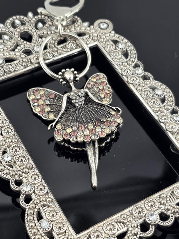 A silver-colored pendant with a butterfly design, adorned with colorful gemstones, is displayed against a dark background.