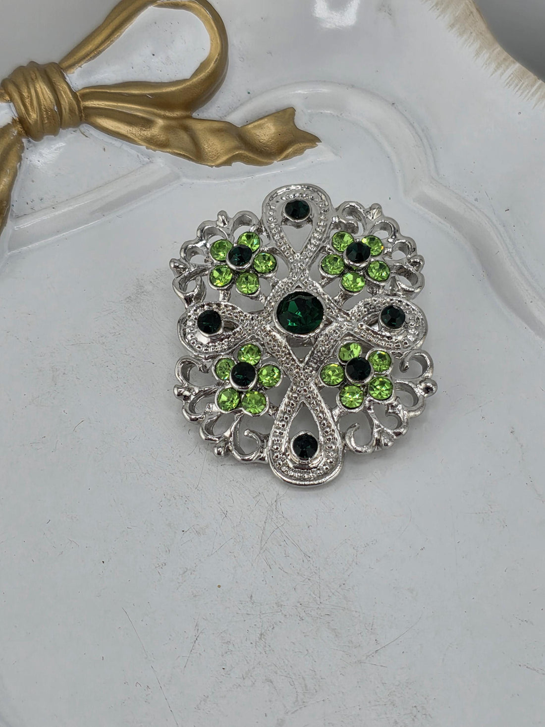 a collection of ornate brooches adorned with green gemstones.