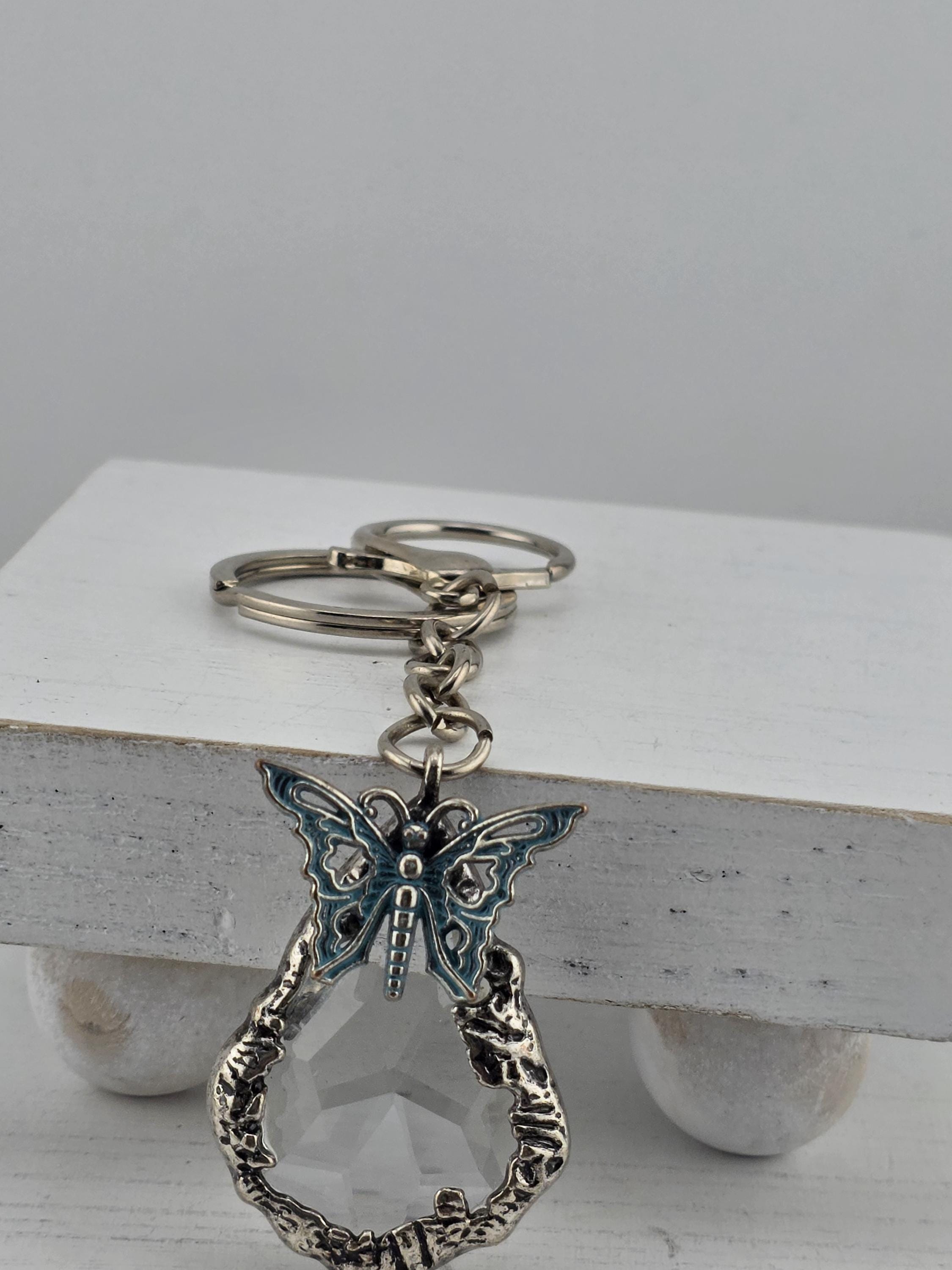 A silver keychain with a butterfly design and a clear gemstone attached to it.