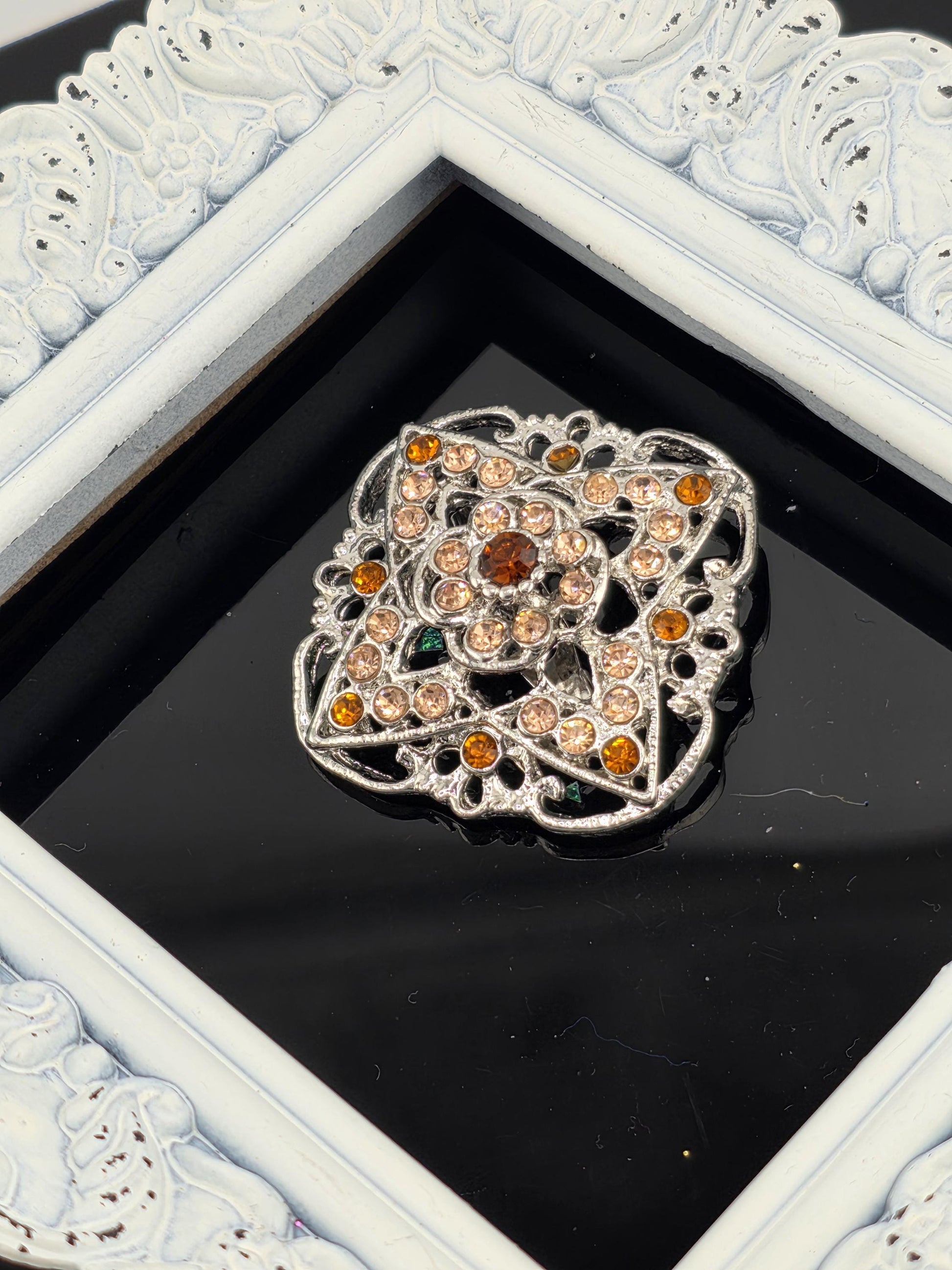 a decorative piece of jewelry with a black background and a white frame.
