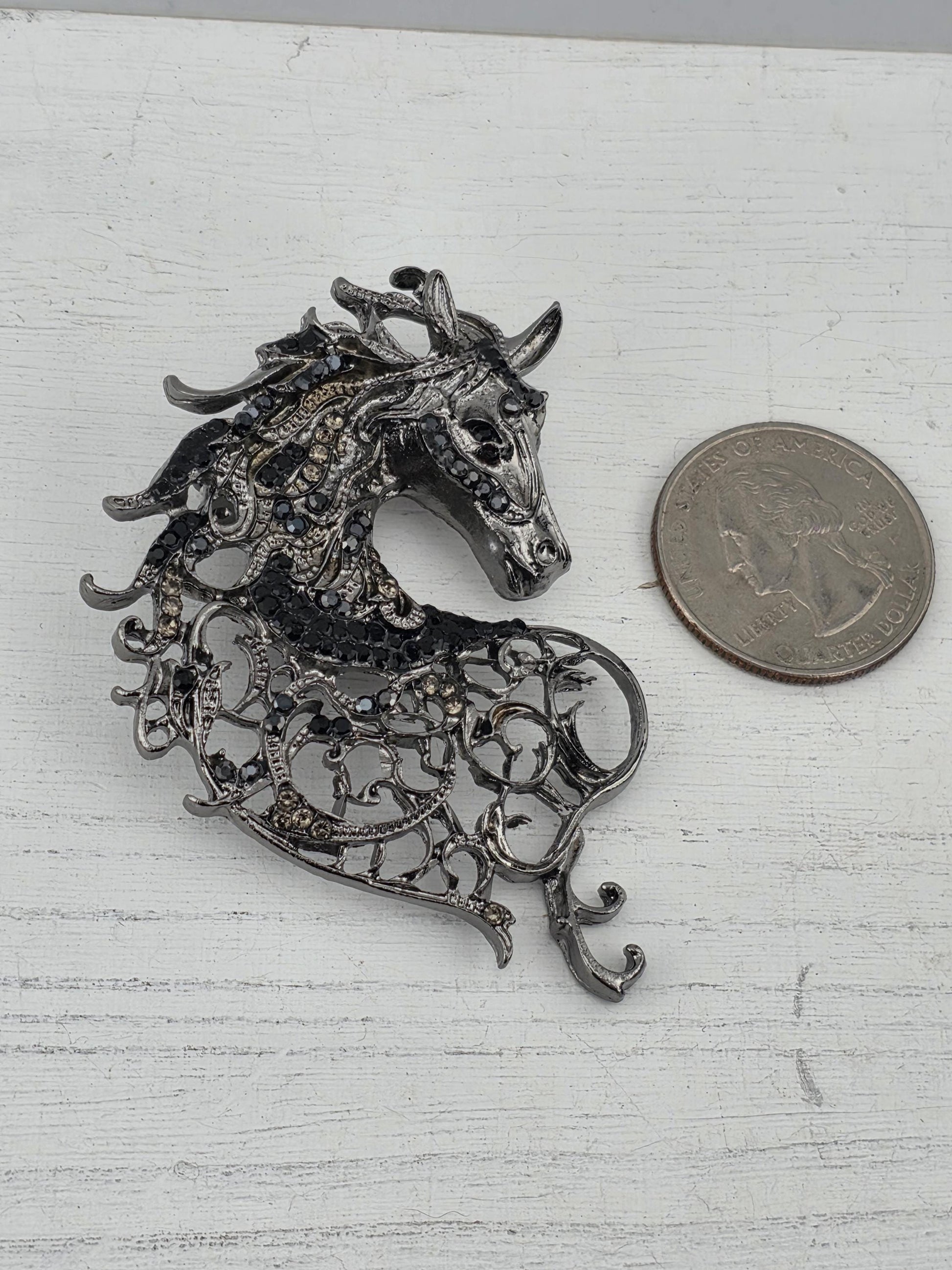 a decorative metal brooch in the shape of a horse's head, with intricate designs and embellishments.