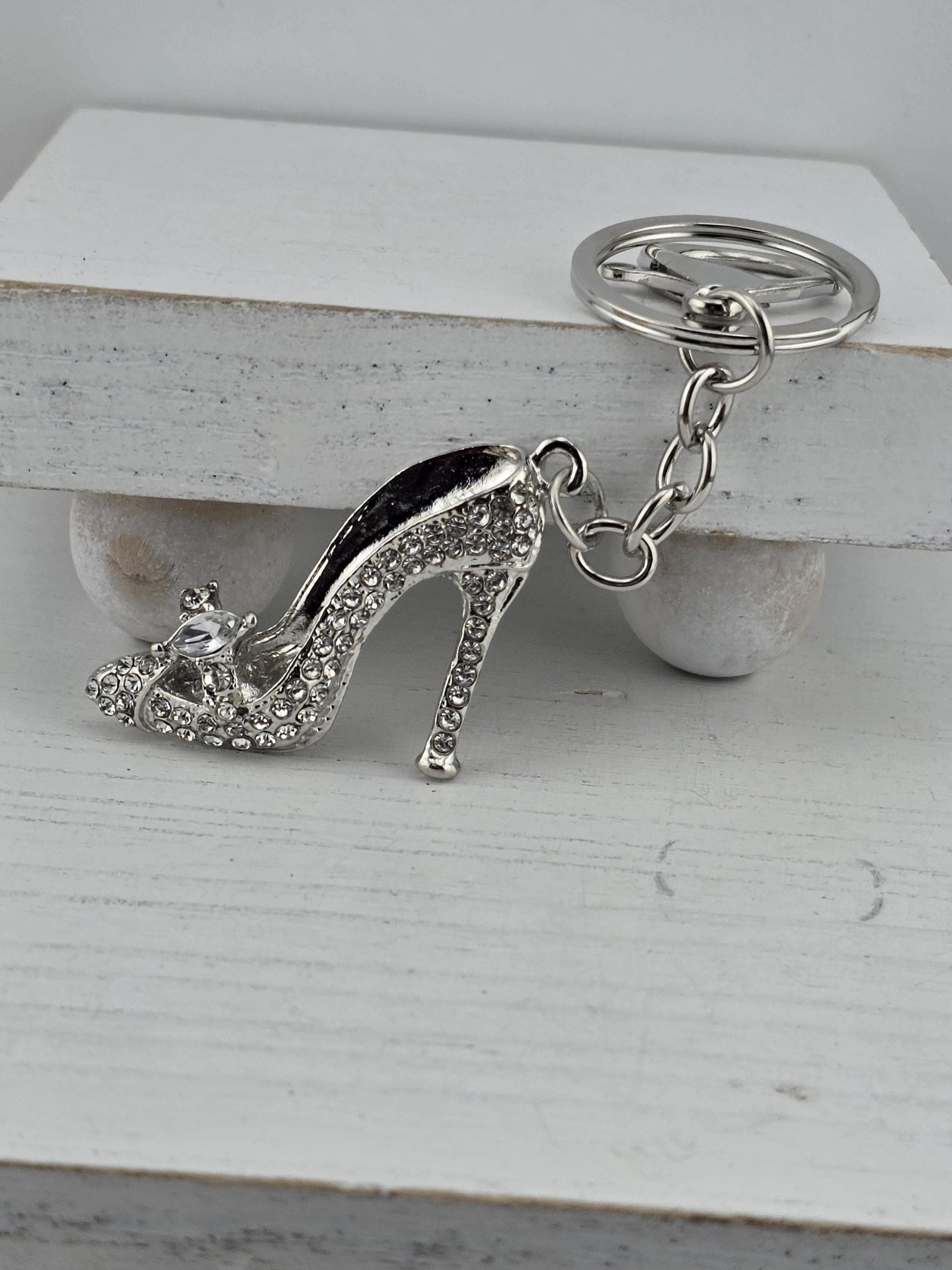 A silver keychain with a high-heeled shoe charm attached to it.
