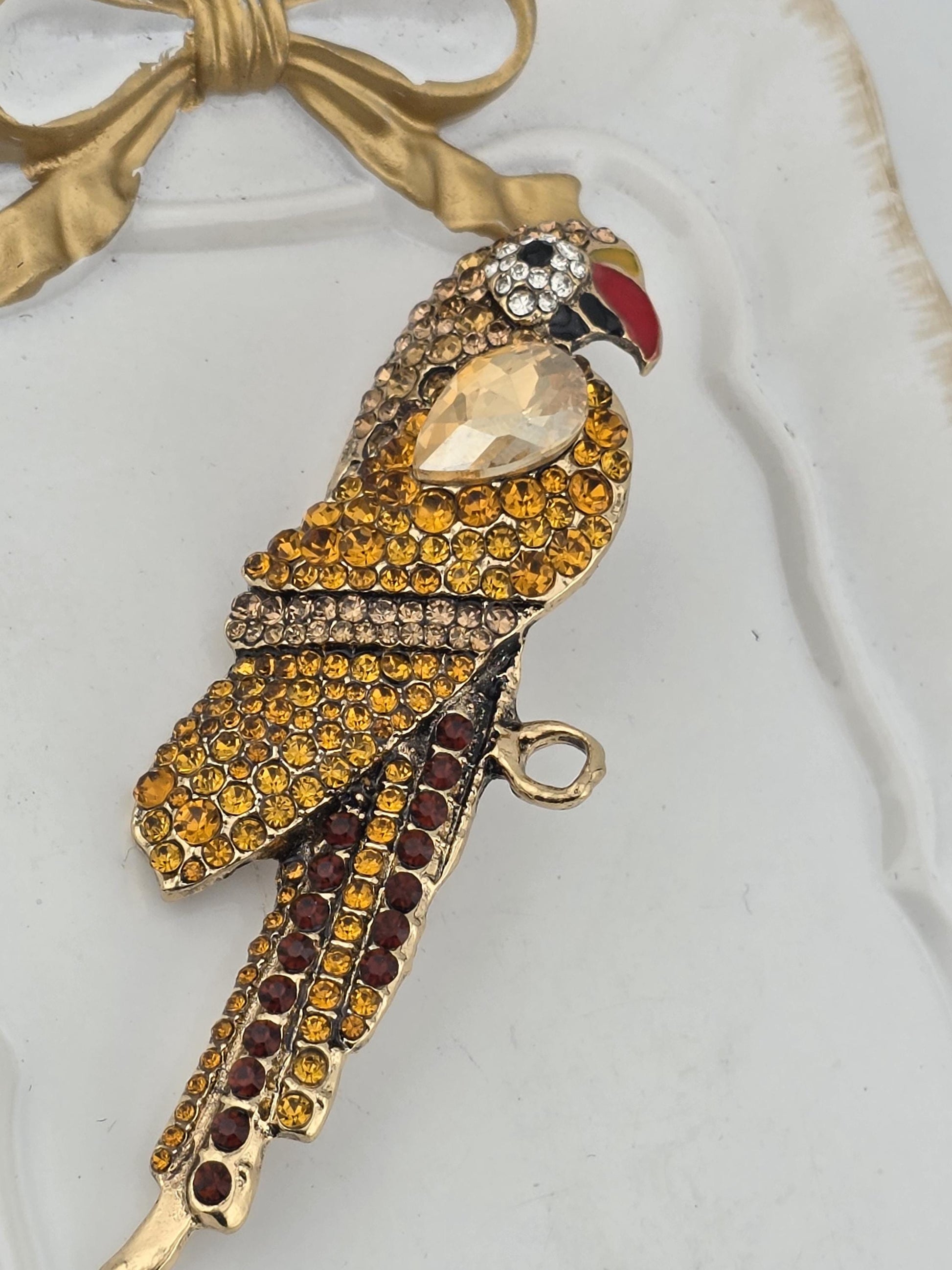 A decorative bird-shaped pendant with a gold and yellow color scheme, adorned with numerous small gemstones.