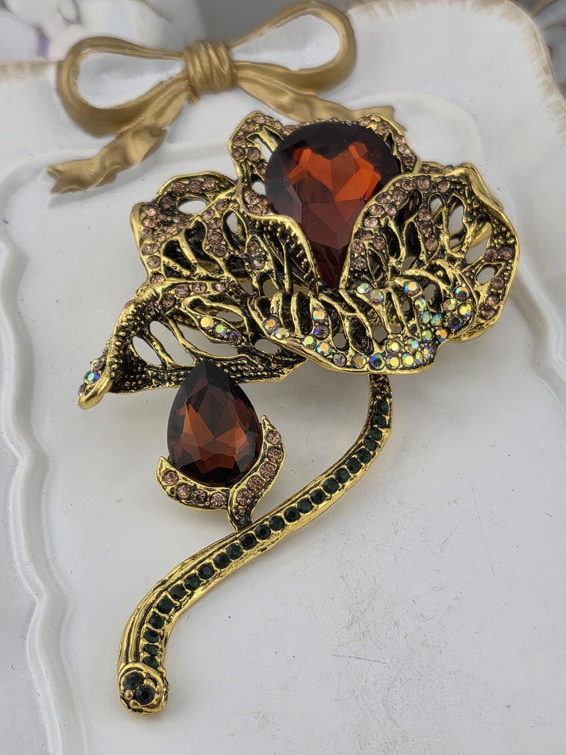 A decorative brooch with a floral design and large, dark-colored gemstones.