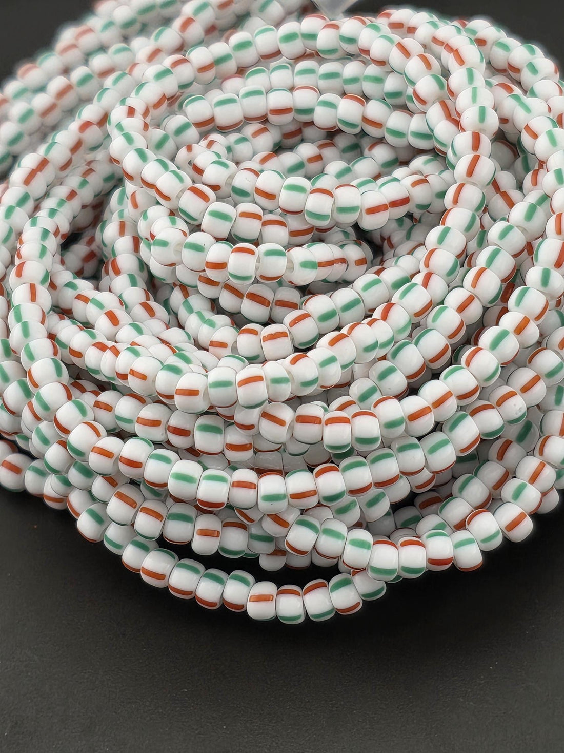 A spiral arrangement of colorful beads in shades of white, green, and orange.