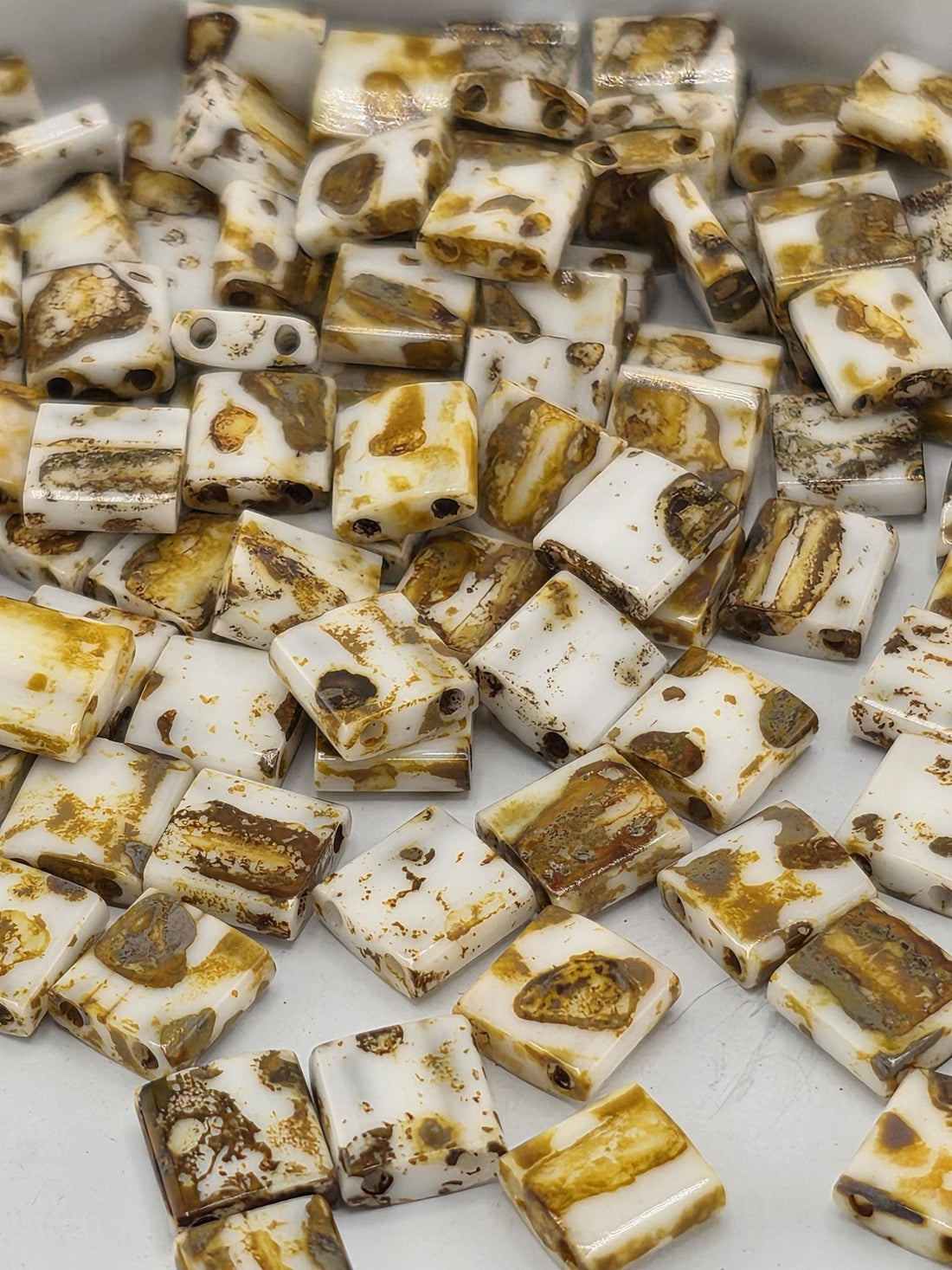 a close-up view of numerous small, square-shaped objects with a brown and white color pattern. The objects appear to be made of a material that resembles wood or a similar natural material.