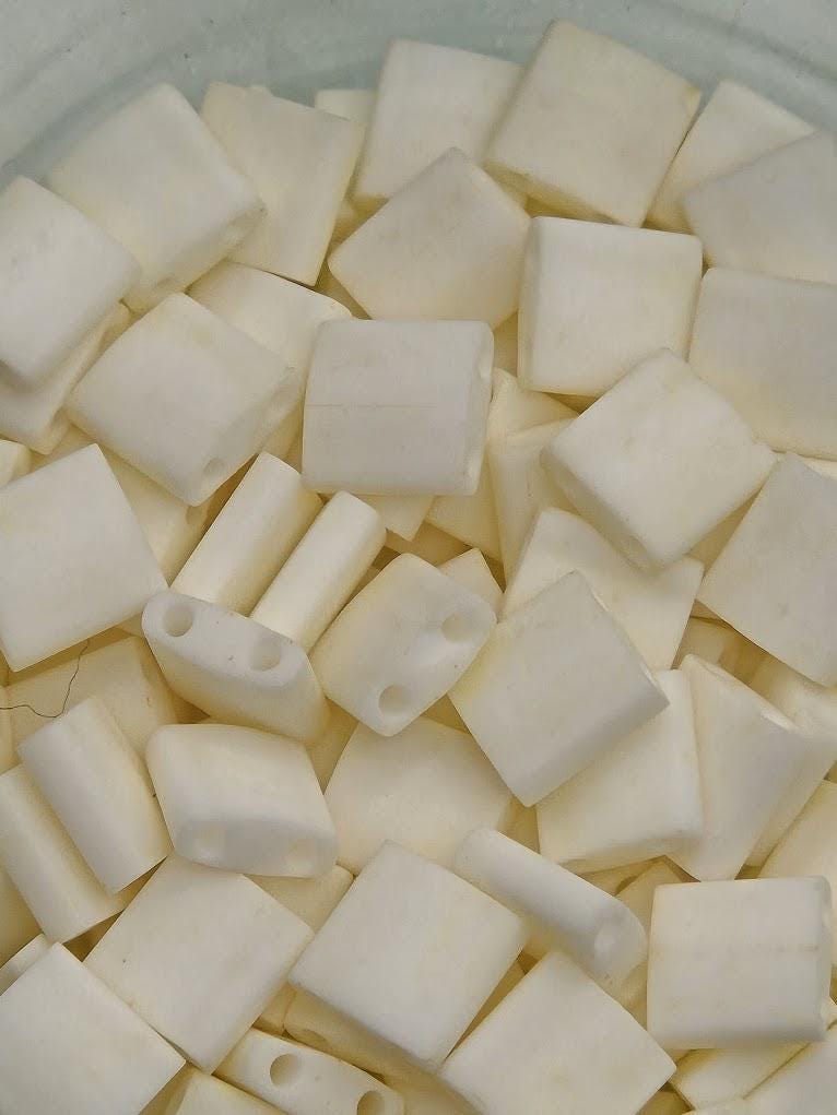 numerous small white cubes or blocks, which appear to be made of a material similar to plastic or a similar substance. The cubes are arranged in a pile or a container, and they are of varying sizes and shapes. The image does not contain any text or other discernible objects or actions.