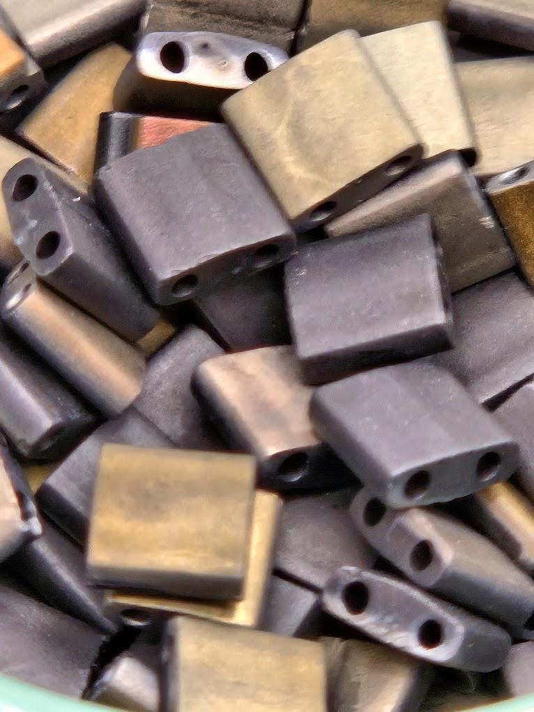 a pile of various metal beads, including copper and brass, with some of them having a textured appearance.