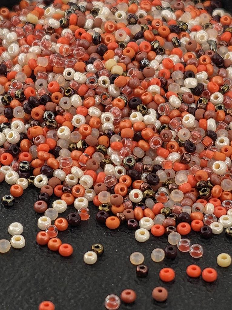 A pile of various colored beads, including white, orange, and brown, scattered on a dark surface.