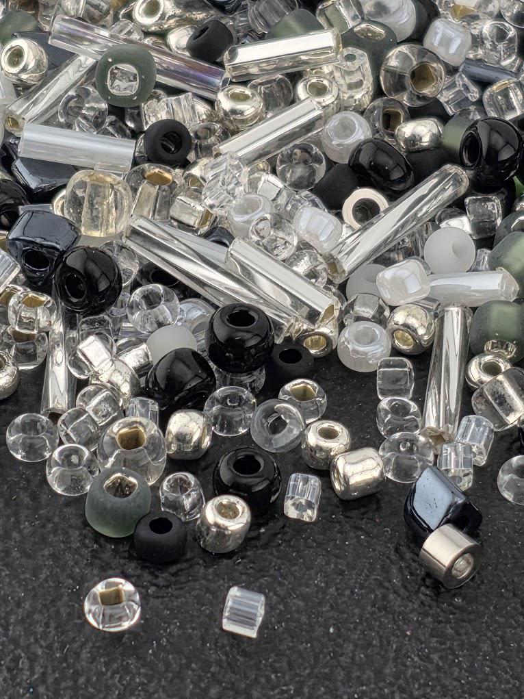 a variety of glass beads and beads in different shapes and sizes, scattered on a dark surface.