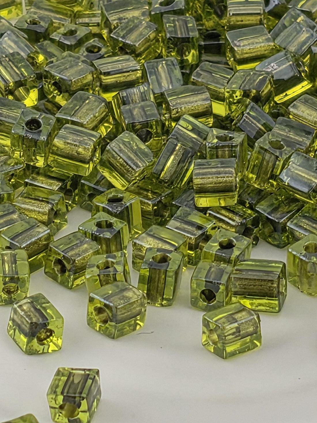 a close-up view of numerous green glass beads or cubes scattered on a surface.