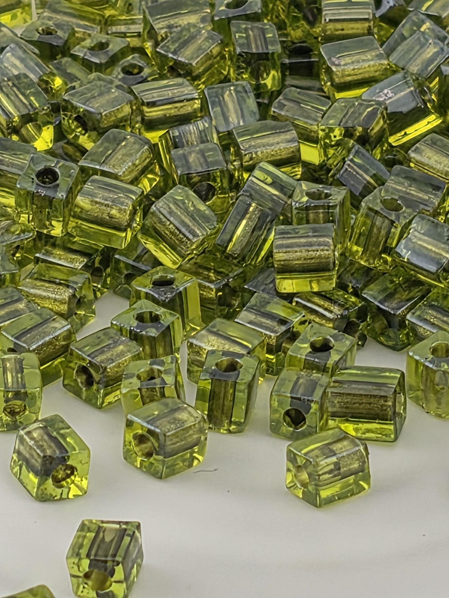 a close-up view of numerous green glass beads or cubes scattered on a surface.