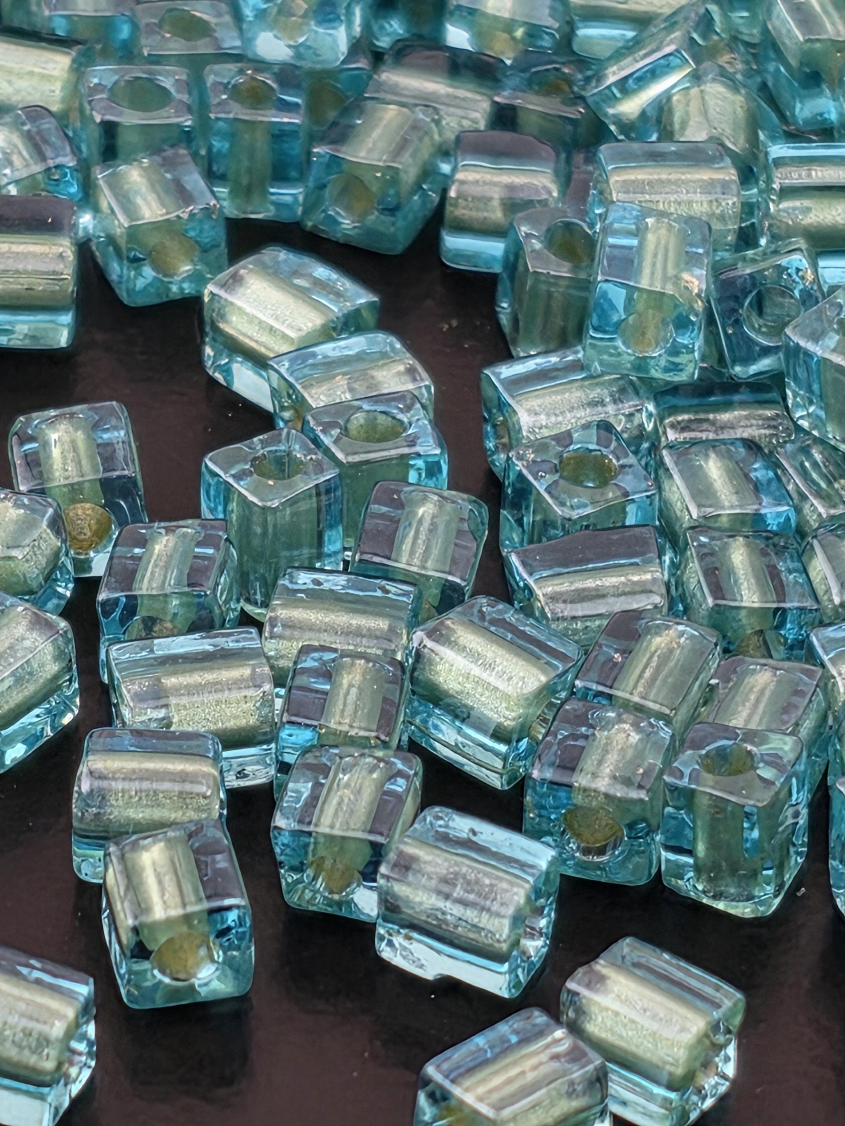 a close-up view of numerous small, clear glass beads scattered across a dark background.