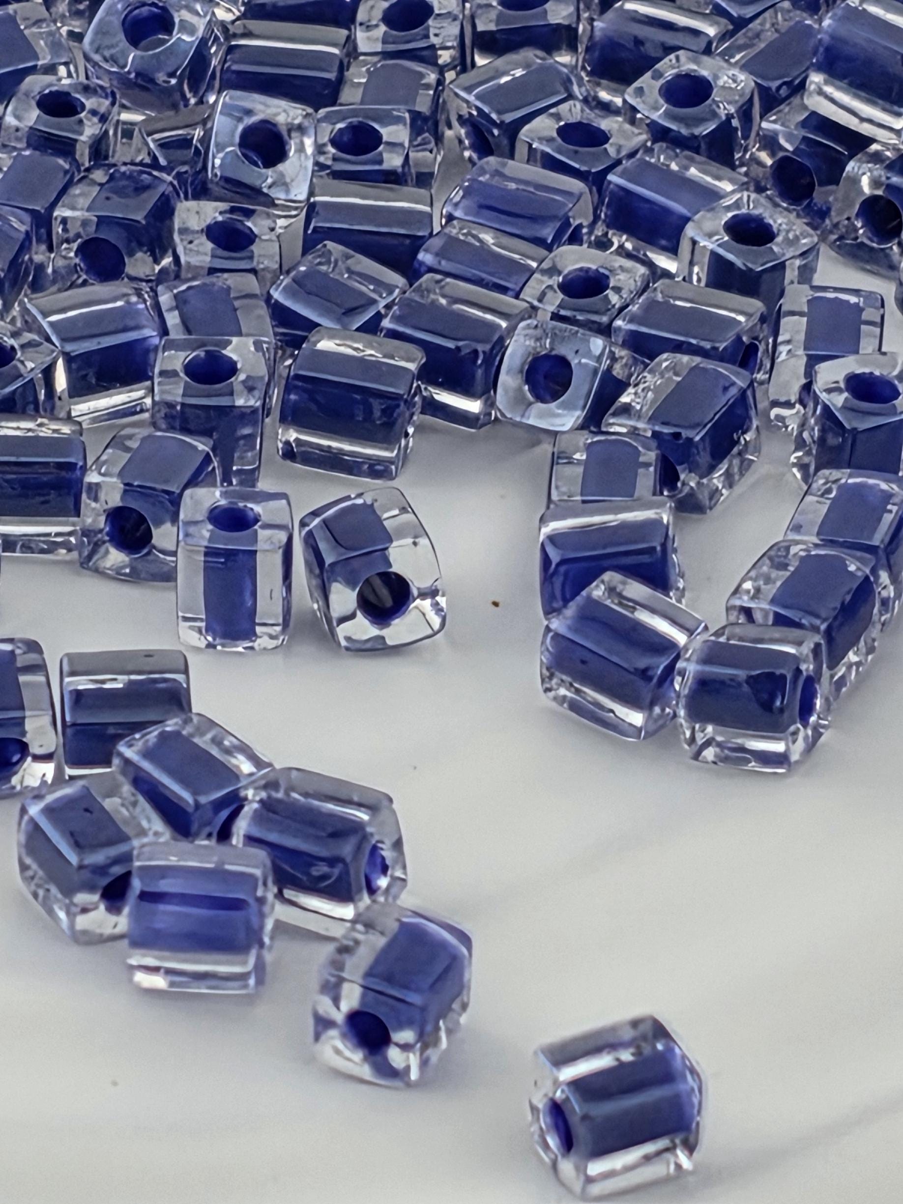 a collection of clear glass beads in various shades of blue, scattered across a white surface.