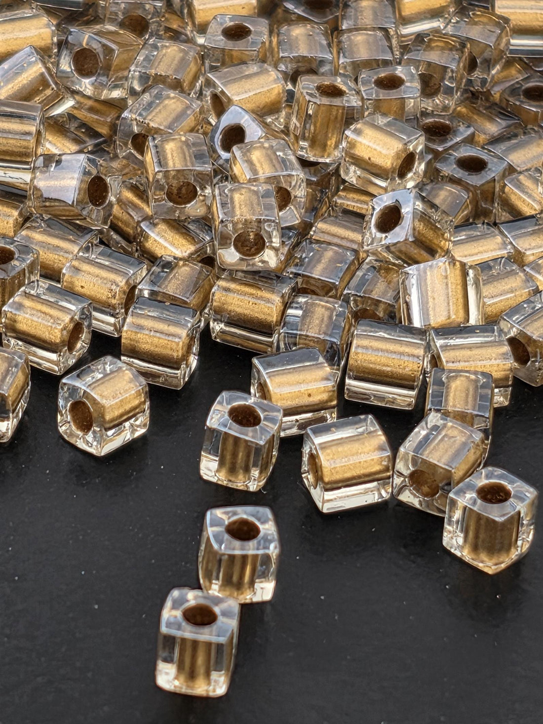 a close-up view of numerous clear glass beads scattered on a dark surface.