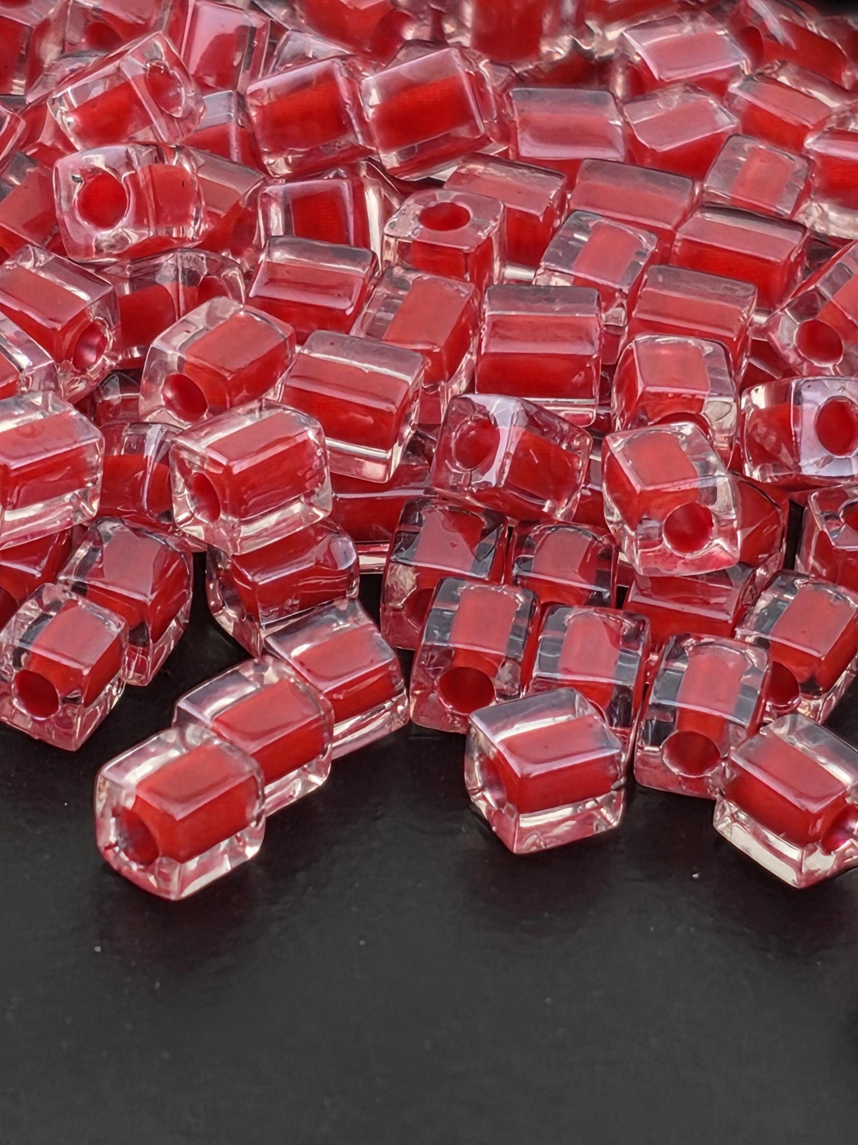 a close-up view of numerous red and clear glass beads or stones, scattered on a dark surface.