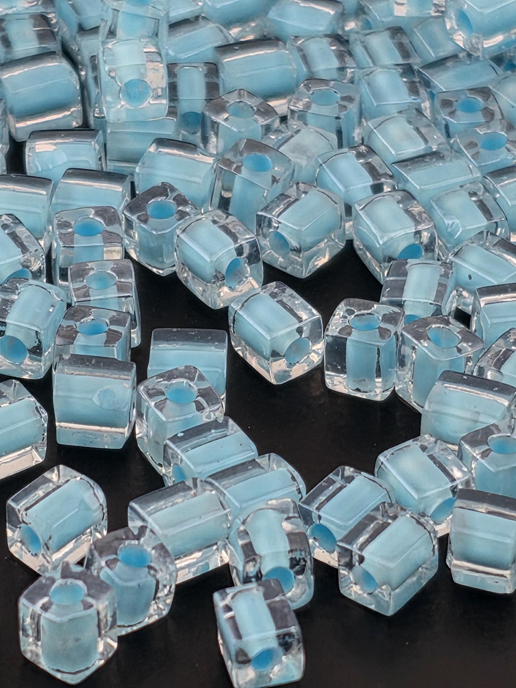 numerous small, clear glass beads scattered across a dark background.