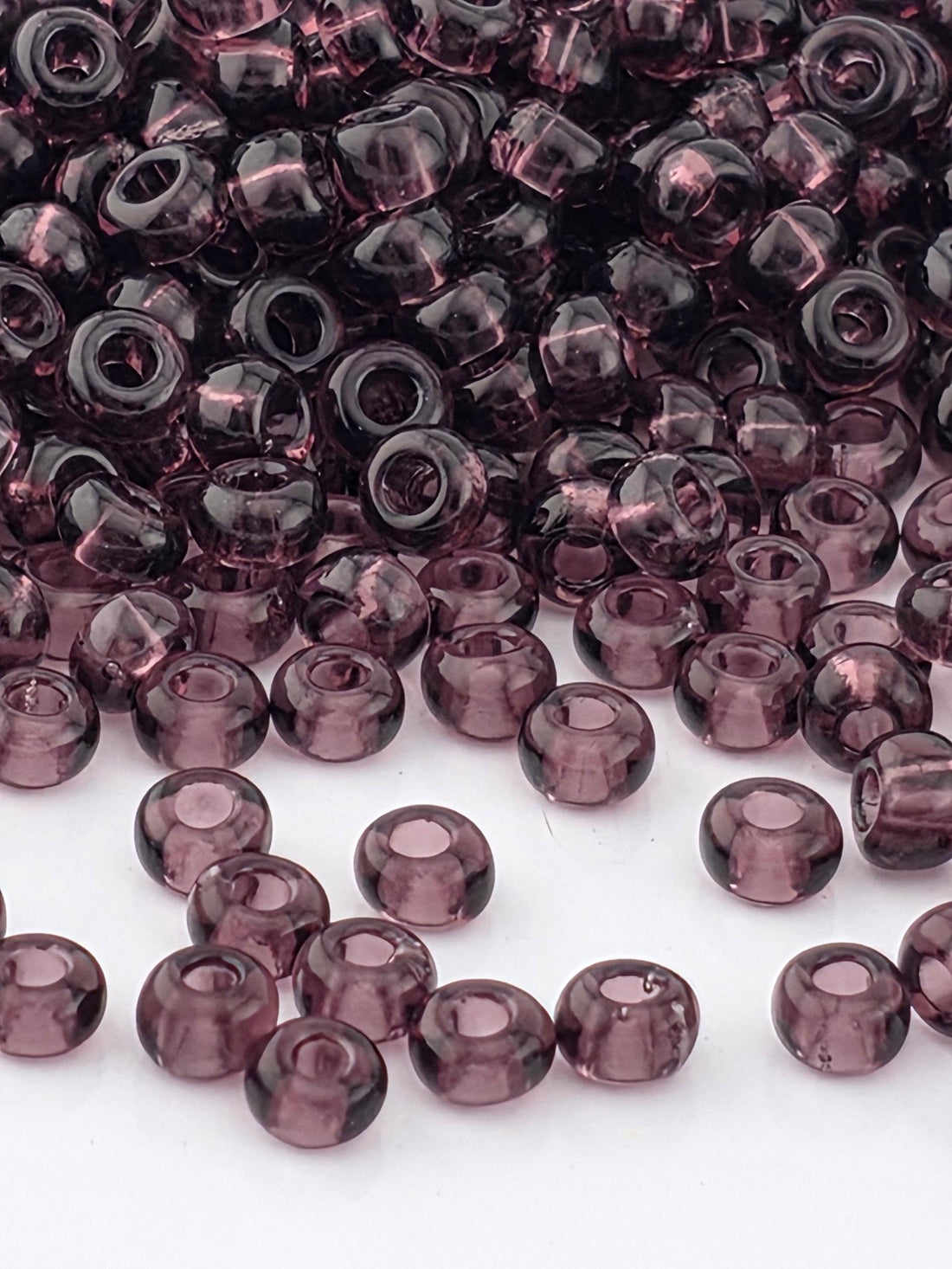 a close-up view of numerous purple glass beads scattered across a white background.
