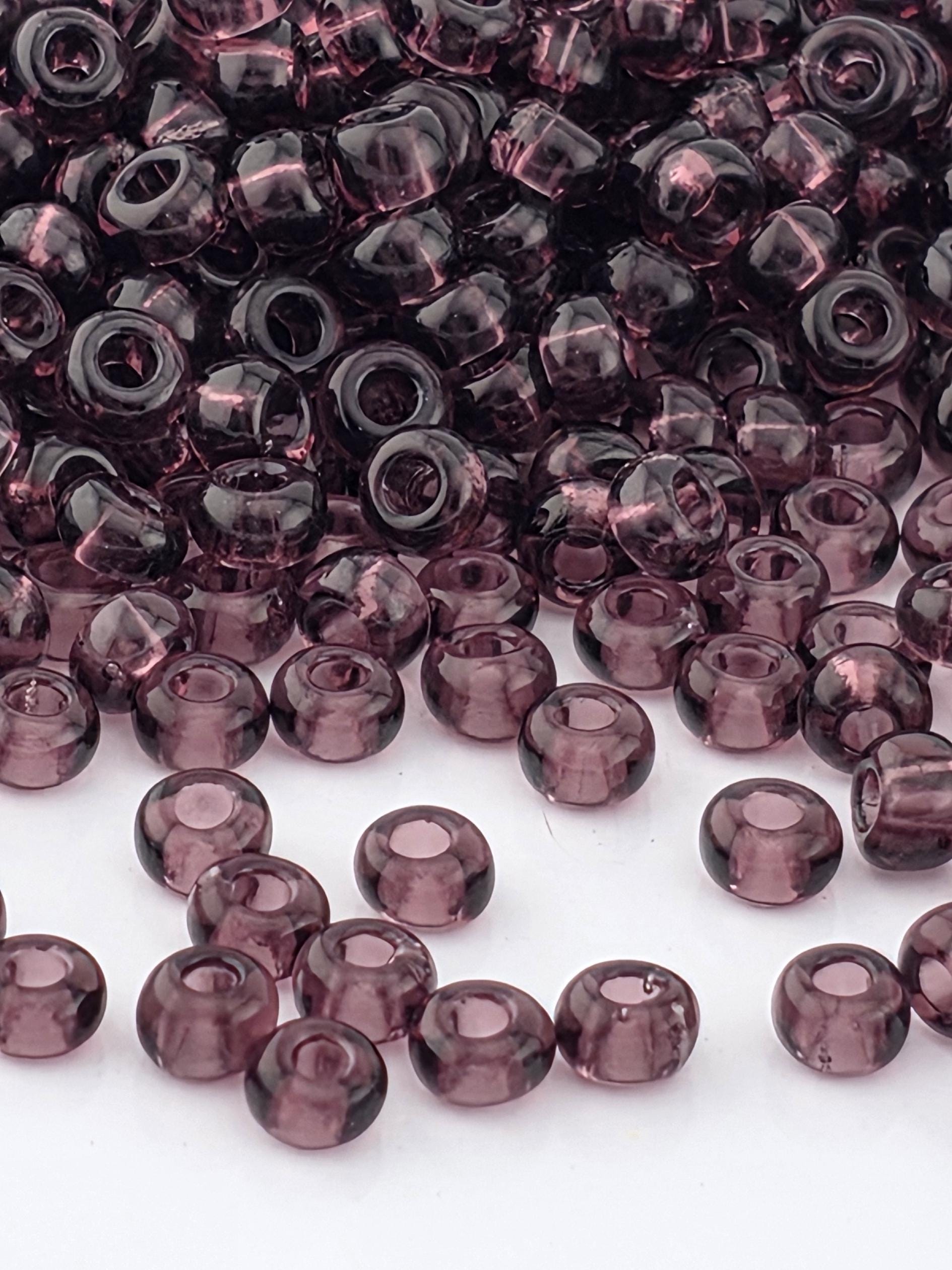 a close-up view of numerous purple glass beads scattered across a white background.