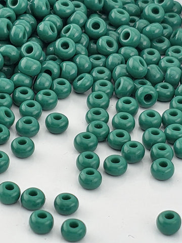 a large pile of green beads scattered on a white surface.