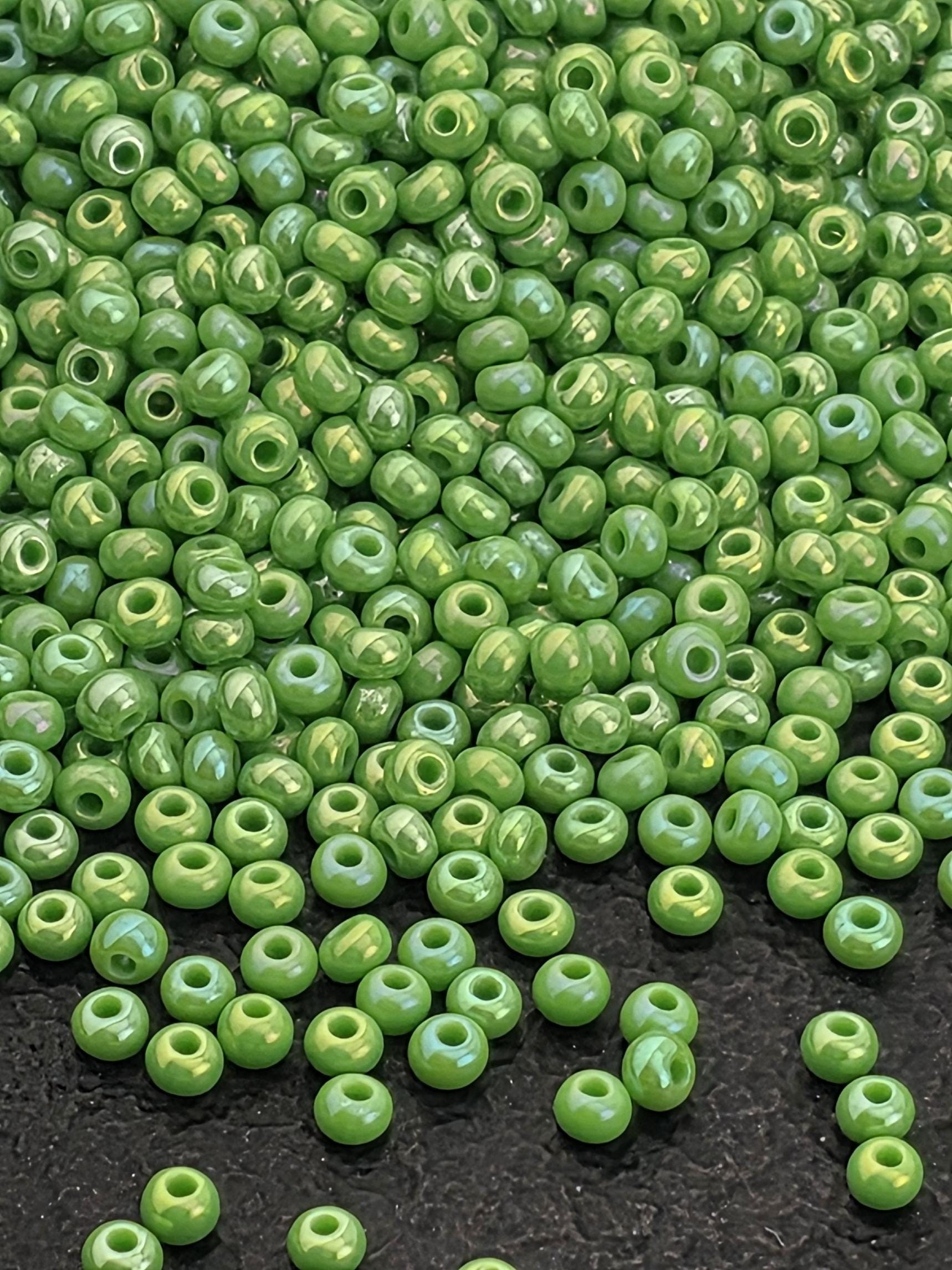 a large pile of green beads scattered on a dark surface.