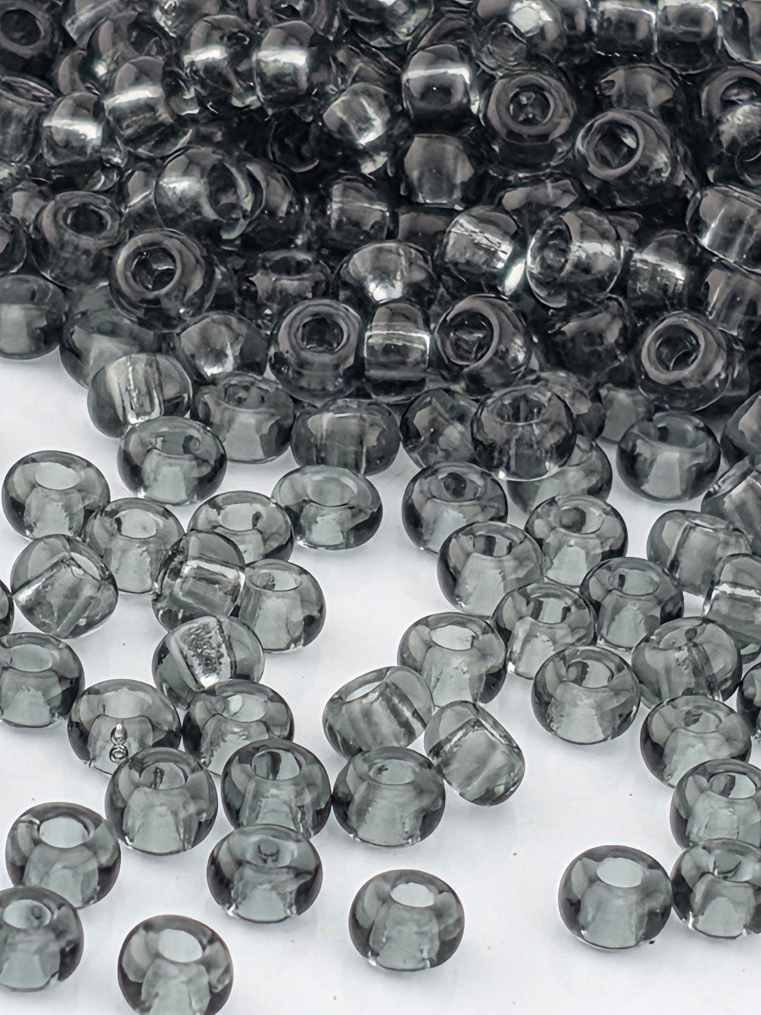 a collection of small, clear beads in various shades of gray, scattered across a white background.
