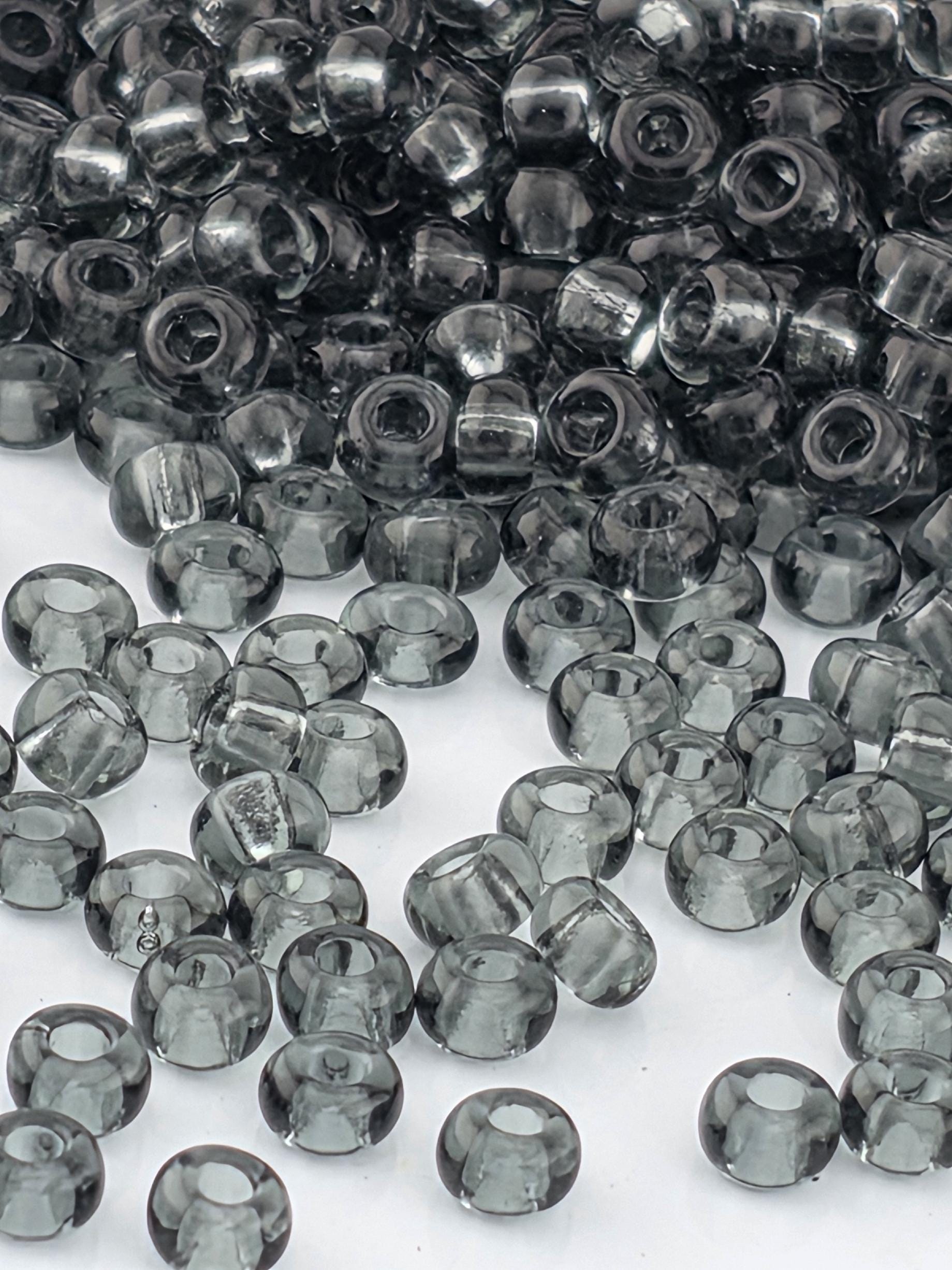 a collection of small, clear beads in various shades of gray, scattered across a white background.