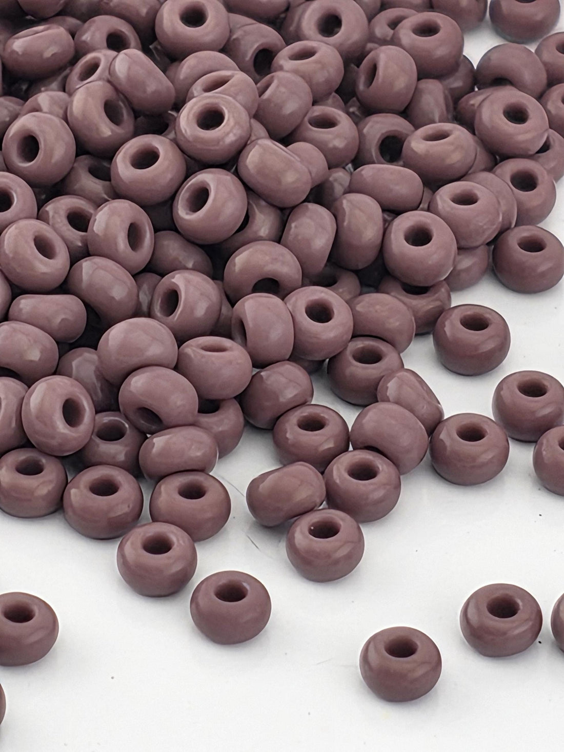 a large pile of small, round beads in various shades of purple.