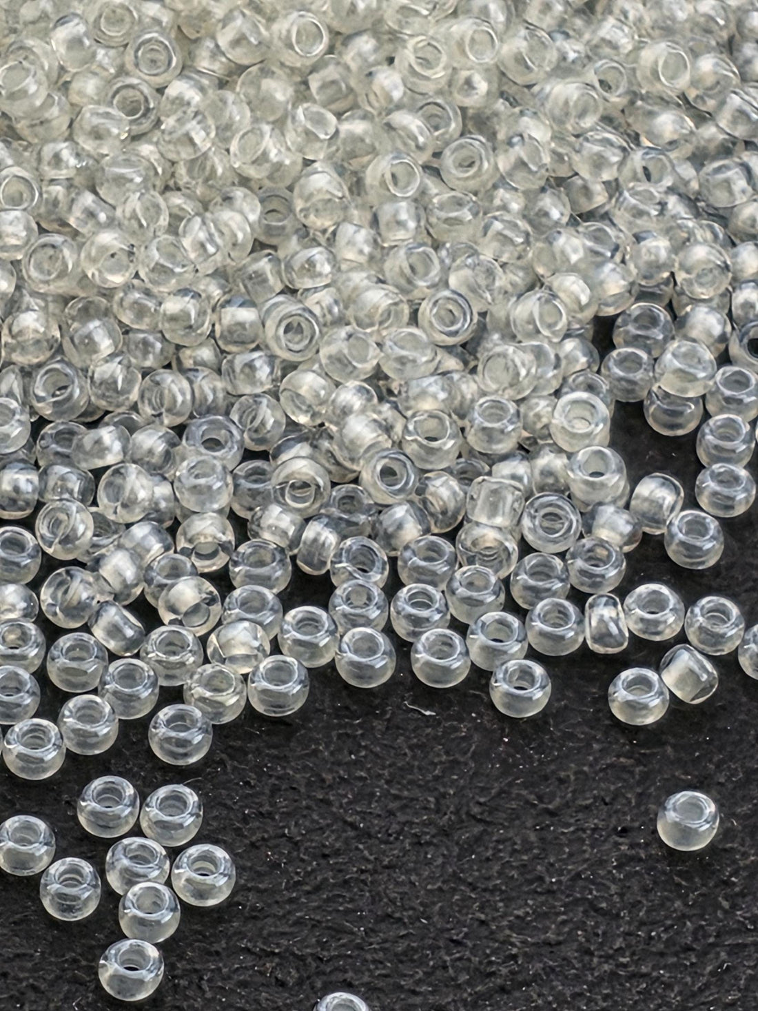 a close-up view of numerous clear plastic beads scattered on a dark surface.
